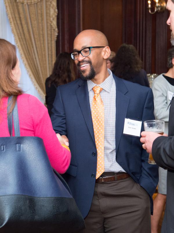 Male and female GSE alumni shaking hands at a networking event.