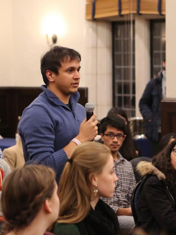 Male student standing with microphone in audience of students