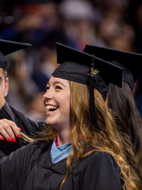 Graduates in caps and gowns laughing.