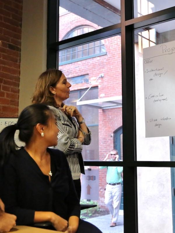 Two women and one man looking intently at chart taped to a window.