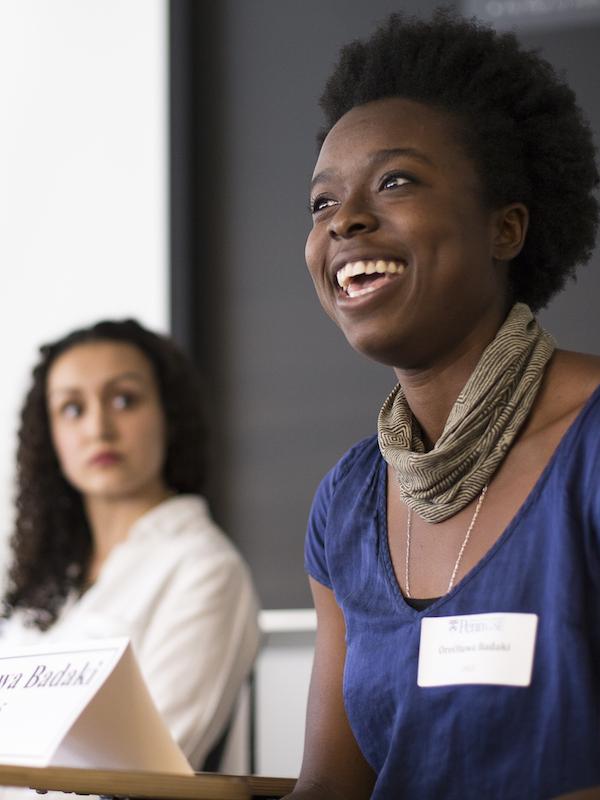 Two women sitting at table with name cards; one is smiling and speaking.