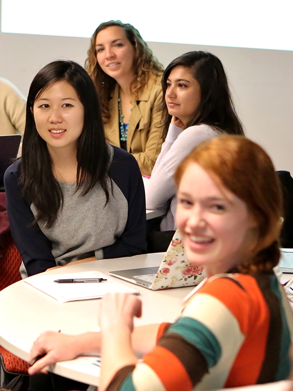 A room full of students sitting around round tables