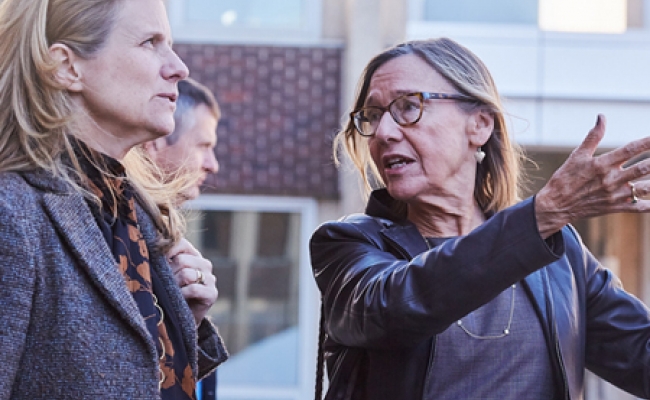 Dean Pam Grossman and President Liz Magill stand outside the Penn GSE building expansion project on a tour as the dean gestures at the construction.