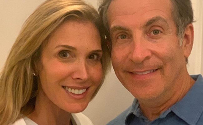 Headshot of a smiling man and woman leaning their heads together. 