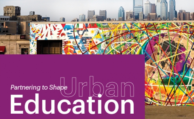 A colorful mural is painted on a South Philadelphia high school. The Philadelphia skyline is visible behind the school. A purple block in the lower left reads, “Spring 2020, Partnering to Shape Urban Education