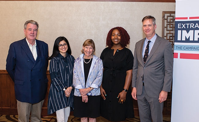 Five Penn GSE faculty wearing business attire stand next to each other and smile