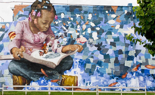 Painting of girl reading book with butterflies flying out.