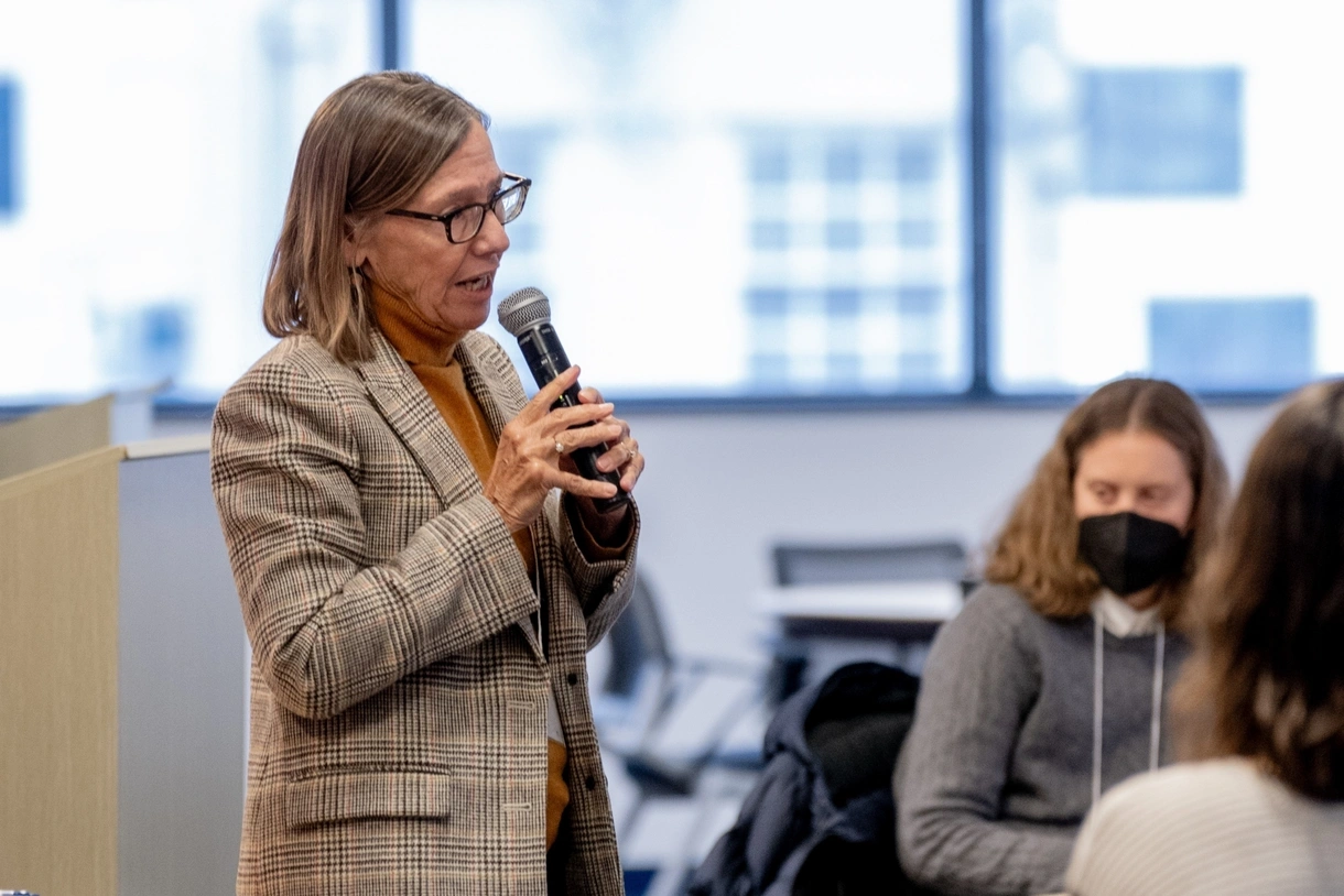 Penn GSE Professor of Education Pam Grossman speaks into a microphone at the front of a conference room while attendees sit and listen.