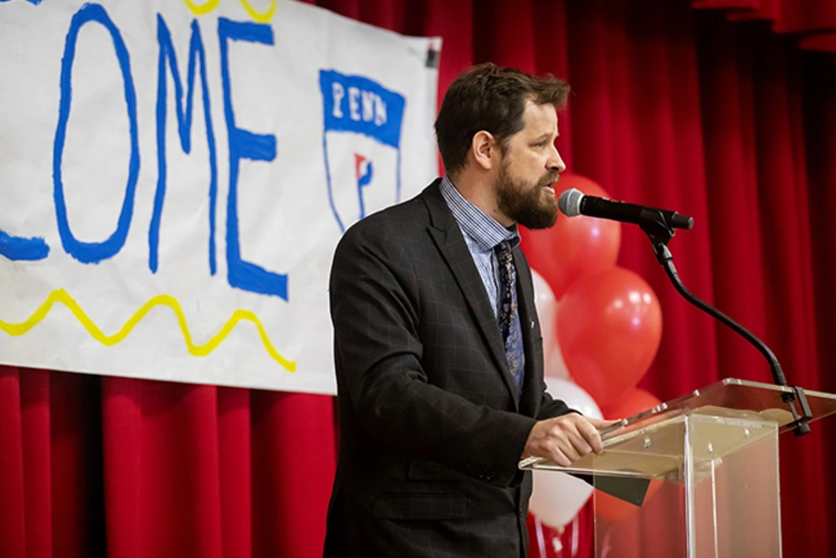 Lea School principal Aaron Gerwer speaks from behind podium at celebration event.
