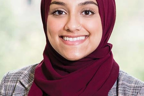 Headshot of Shahara Ahmed wearing a maroon head covering against a blurred backdrop.