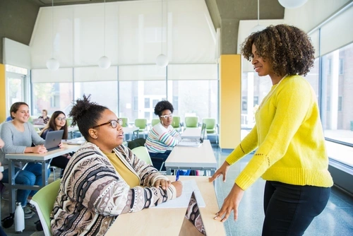 Teacher speaking with a student at the front of the class