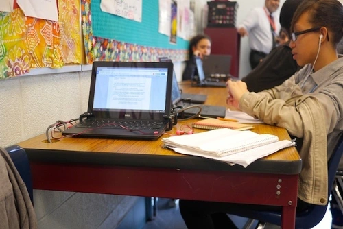 Laptop on table with students
