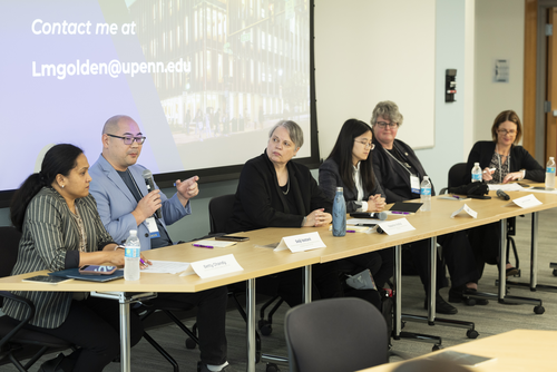 Six people in discussion sit a long table in front of name tags