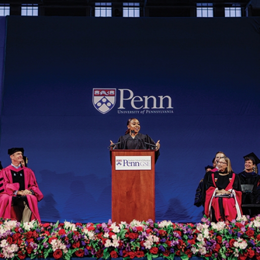 Abbott Elementary creator Quinta Brunson stands at a podium flanked on either side by Penn GSE faculty while delivering remarks at the 2023 commencement ceremony.
