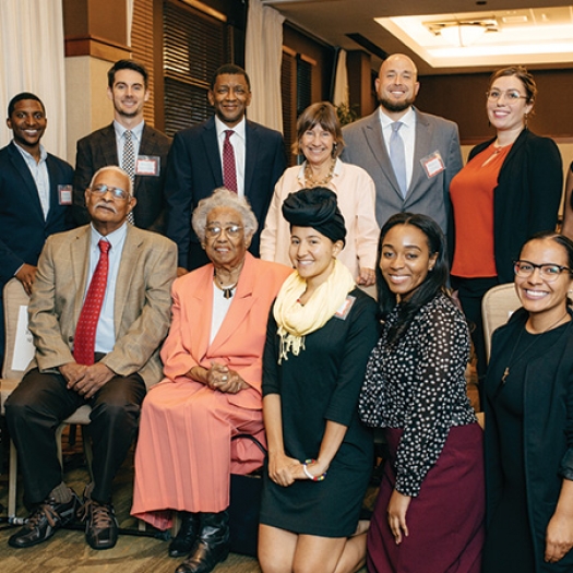 Dr. Constance E. Clayton sits in a peach colored skirt and blazer, surrounded by attendees at the 2016 Constance E. Clayton Lecture