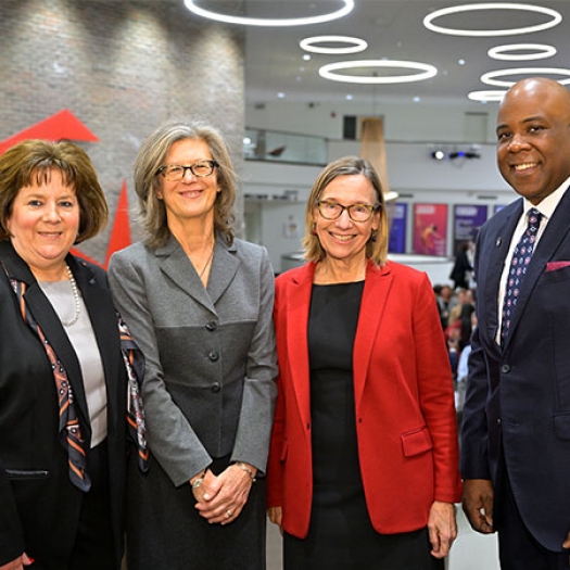 Susan Basso, Diane Eynon, Pam Grossman, and Lawrence P. Ward standing together at a gala event, dressed in suits and smiling.