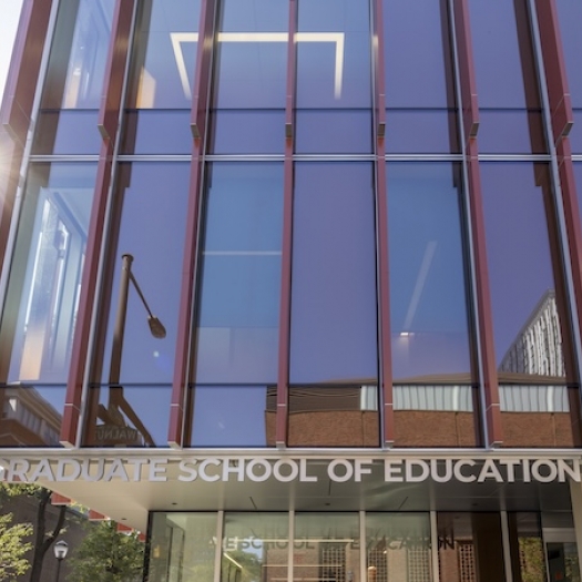 The sun flares on the front of the GSE building with the Graduate School of Education sign clearly visible