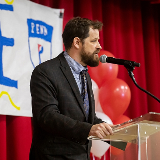 Lea School principal Aaron Gerwer speaks from behind podium at celebration event.