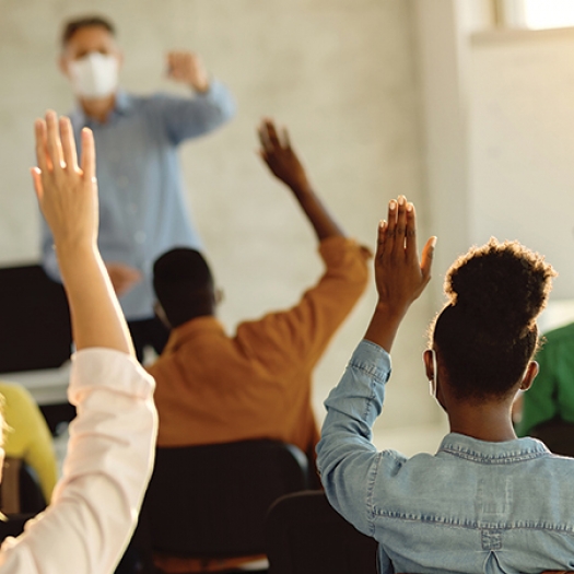 Students raising their hands in a classroom.