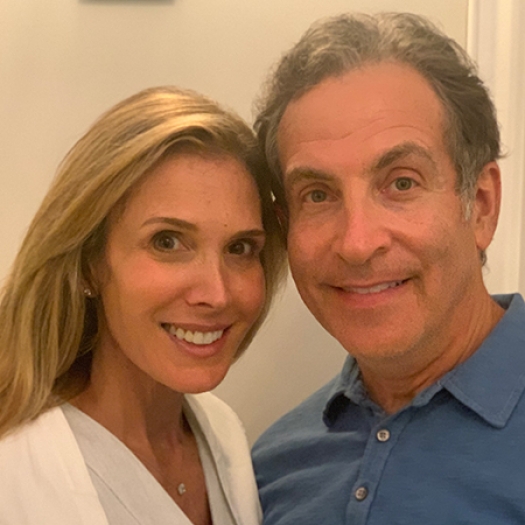 Headshot of a smiling man and woman leaning their heads together. 