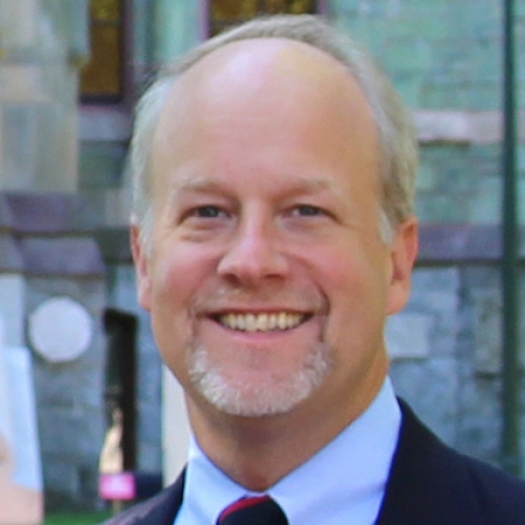 Man smiling in front of campus building