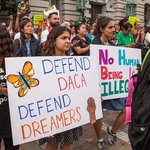 People hold signs in favor of DACA at a rally