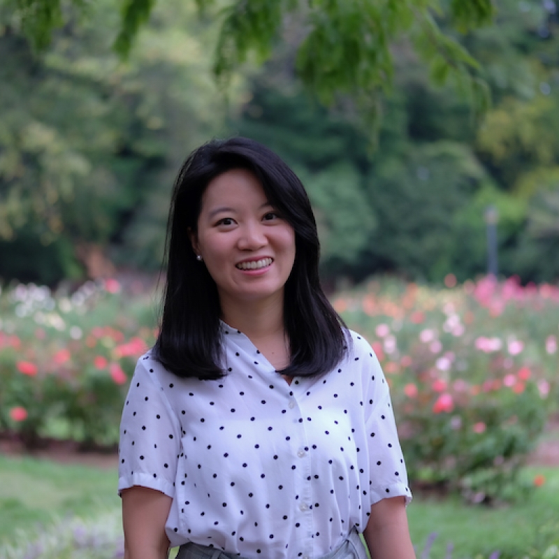 Lys Lin standing in front of a flower garden