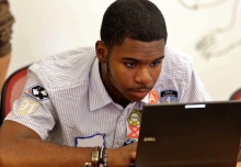 A student sits and works at a laptop computer. 