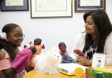 A student and a school counselor use dolls during a counseling session.