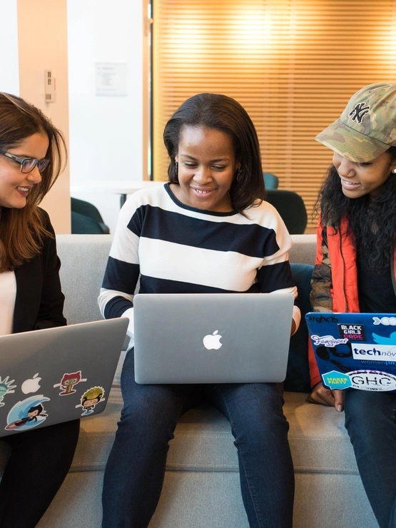 Three females sitting with laptops smiling