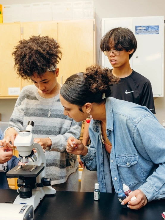 a group of multicultural students engage with a microscope within a classroom environment