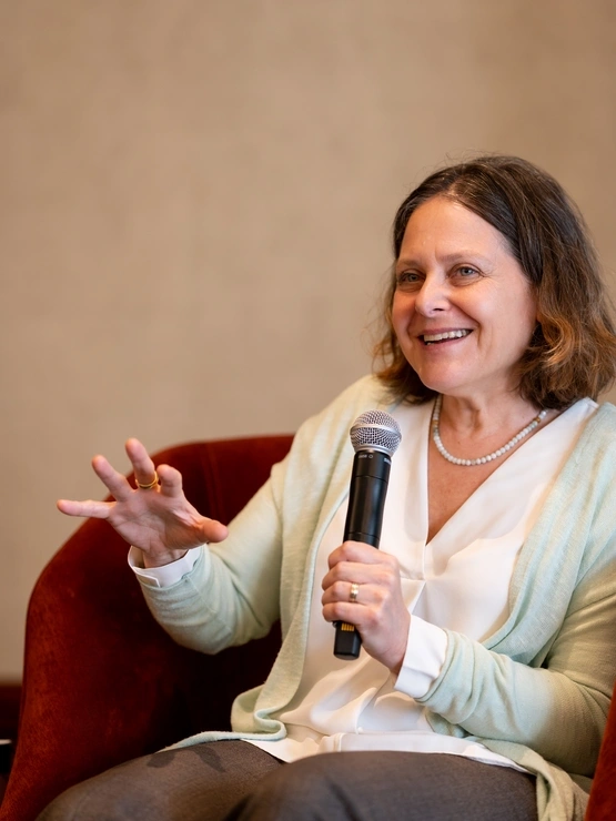 a woman in a light top is smiling while speaking into a microphone