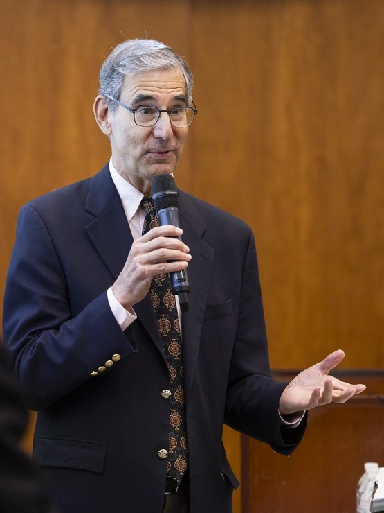Michael Golden, wearing a suit and tie, speaks at a microphone