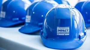 Shiny blue hardhats with the “Extraordinary Impact” logo sit on a table.