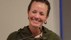 Ali Michaels smiling in front of microphone.