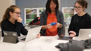 Three young people sitting around laptops