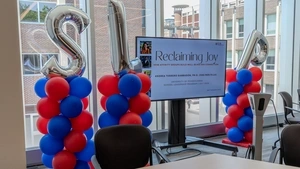 Balloon arrangements in Penn Red and Blue with silver "S," "L," and "P" balloon letters around a screen reading "Reclaiming Joy"