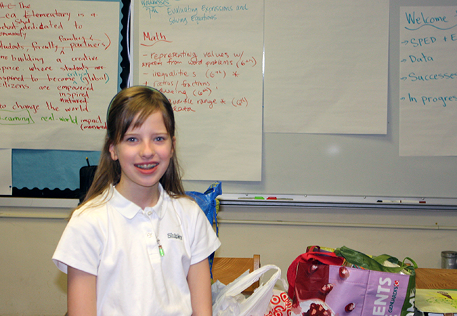 Young girl in classroom with shopping bags.