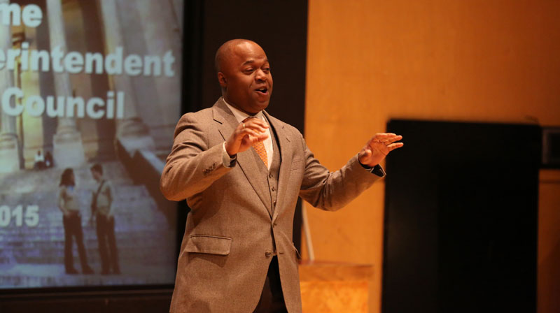 A speaker presenting in front of a screen