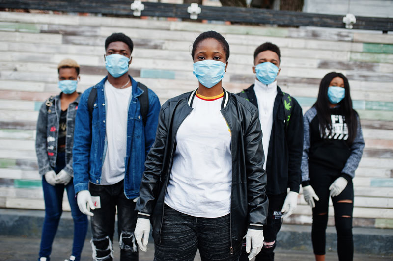 5 people standing outdoors with surgical masks and gloves, all facing forward