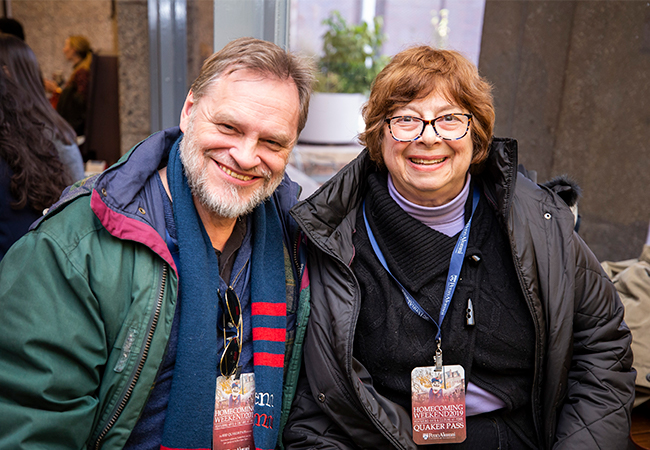 A man and a woman are both smiling and wearing winter coats