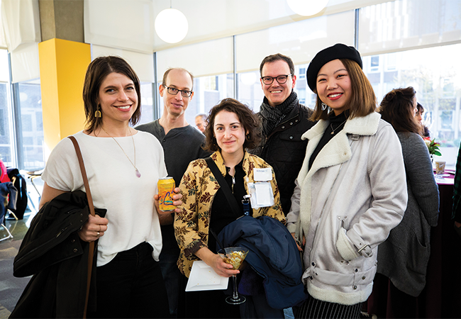 Five people at an event stand together, smiling