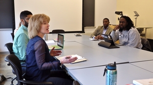 Laura Perna in a classroom with a roundtable of graduate students.